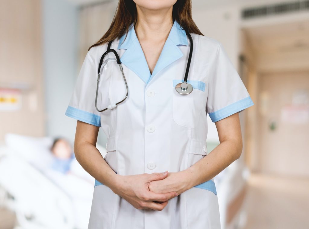 wanita dengan kemeja putih berkancing dan stetoskop biru